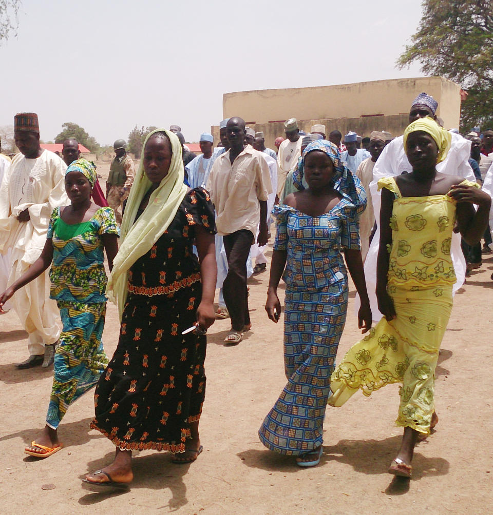 FILE - In this Monday April 21, 2014 file photo, four female students of the government secondary school Chibok, who were abducted by gunmen and reunited with their families, walk in Chibok, Nigeria. A civil society group says Wednesday April 30, 2014, that villagers are reporting that scores of girls and young women who were recently kidnapped from a school in Nigeria are being forced to marry Islamic extremists. A federal senator for the area in northeast Nigeria wants the government to get international help to rescue the more than 200 missing girls kidnapped by Boko Haram from a school two weeks ago. (AP Photo/ Haruna Umar, File)