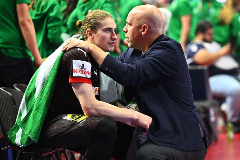 DHB sports director Axel Kromer comforts Germany's Juri Knorr (L) after the the 2024 EHF European Men's Handball semi-finals match between Denmark and Germany at Lanxess Arena. Tom Weller/dpa