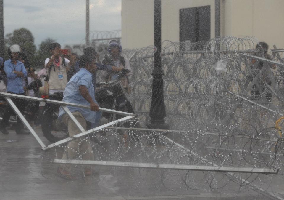 A protester supporting the opposition Cambodia National Rescue Party (CNRP) tries to remove barbed wire barricades during clashes with police near the Royal Palace in central Phnom Penh September 15, 2013. (REUTERS/Samrang Pring)