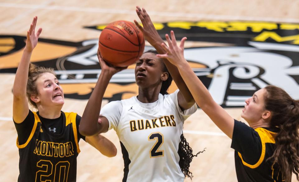 Quaker Valley's Oumou Thiero tries to shoot around  Montour's Julia Cox, left, during their game Friday at Montour High School. [Lucy Schaly/For BCT]