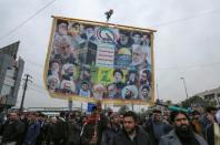 Des partisans du Hachd al-Chaabi, coalition de factions irakiennes pro-Iran, manifestant dans les rues de Bagdad le 2 janvier 2022 avec une pancarte où il est notamment écrit "Mort à l'Amérique" (AFP/Sabah ARAR)