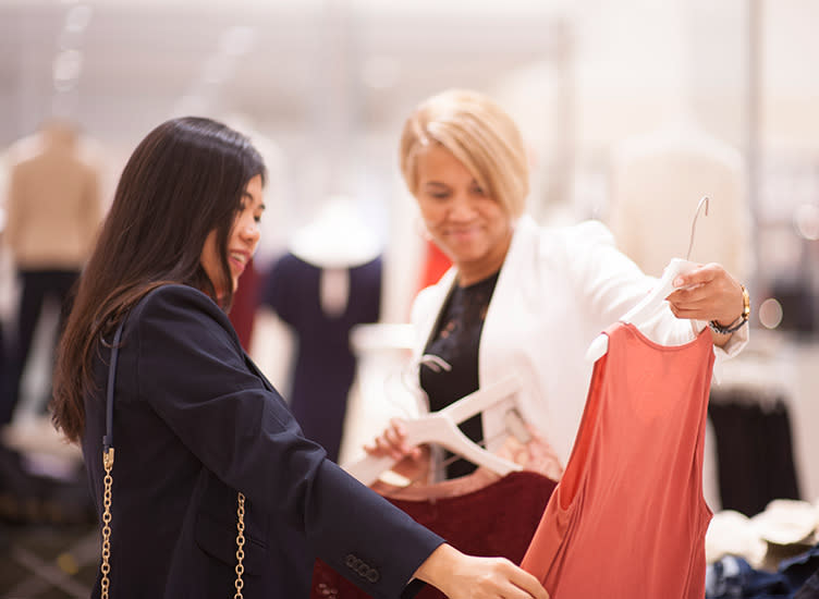 Two woman looking at a top in a clothing store.