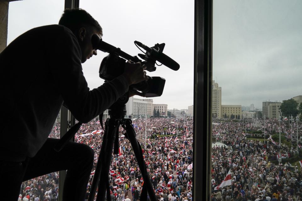 A cameraman films as Belarusian opposition supporters rally at Independence Square in Minsk, Belarus, Sunday, Aug. 23, 2020. A vast demonstration with many thousands of protesters demanding the resignation of Belarus' authoritarian president are rallying in the capital Sunday, continuing the public dissent since the disputed presidential election. (AP Photo/Evgeniy Maloletka)