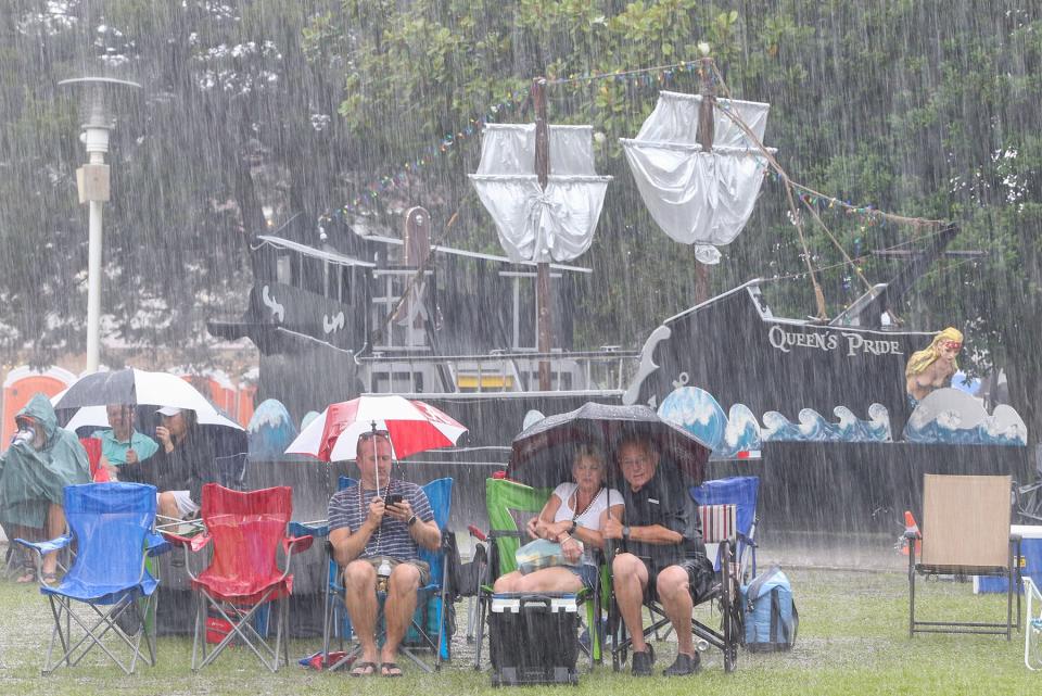 People try to stay dry in a deluge of rain during the Friday night skirmish at the 66th Billy Bowlegs Pirate Festival at the Fort Walton Beach Landing.