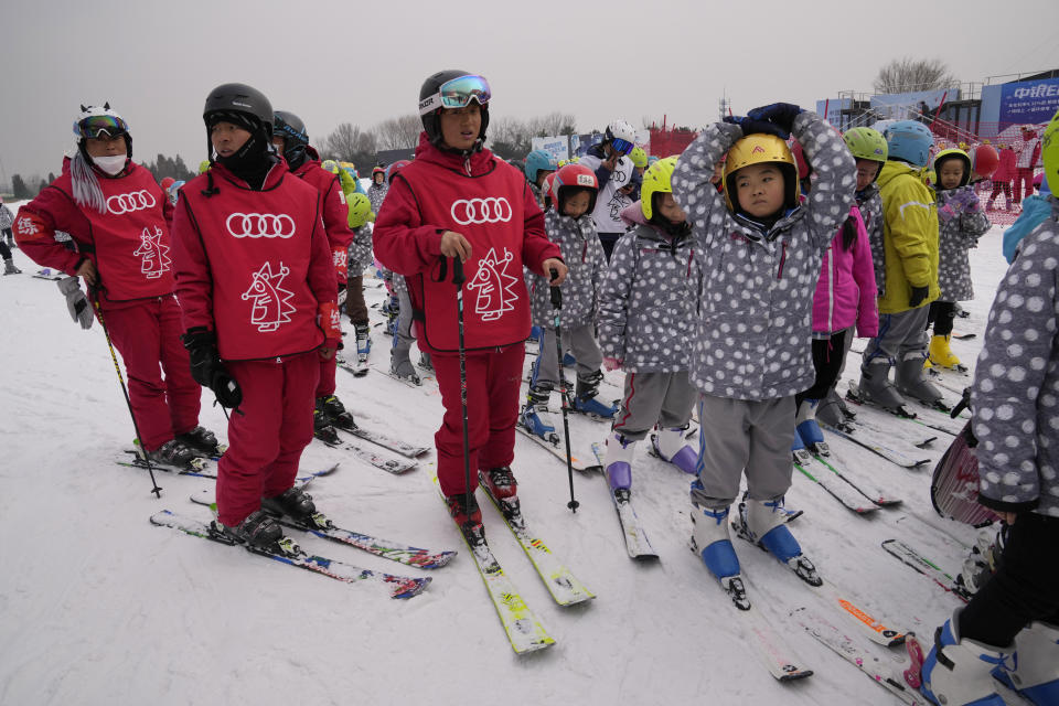 School children wait in line to go onto the slope with ski instructors at the Vanke Shijinglong Ski Resort in Yanqing on the outskirts of Beijing, China, Thursday, Dec. 23, 2021. The Beijing Winter Olympics is tapping into and encouraging growing interest among Chinese in skiing, skating, hockey and other previously unfamiliar winter sports. It's also creating new business opportunities. (AP Photo/Ng Han Guan)