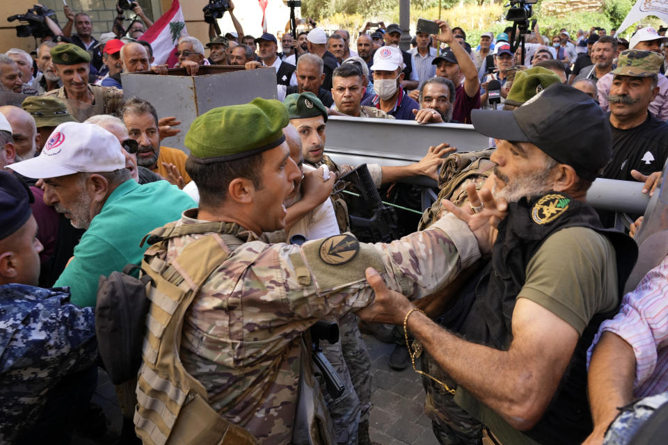 A soldier, left, scuffle with a retired army member as he tries to enter to the parliament building while the legislature was in session discussing the 2022 budget, during a protest in downtown Beirut, Lebanon, Monday, Sept. 26, 2022. The protesters demanded an increase in their monthly retirement pay, decimated during the economic meltdown. (AP Photo/Bilal Hussein)