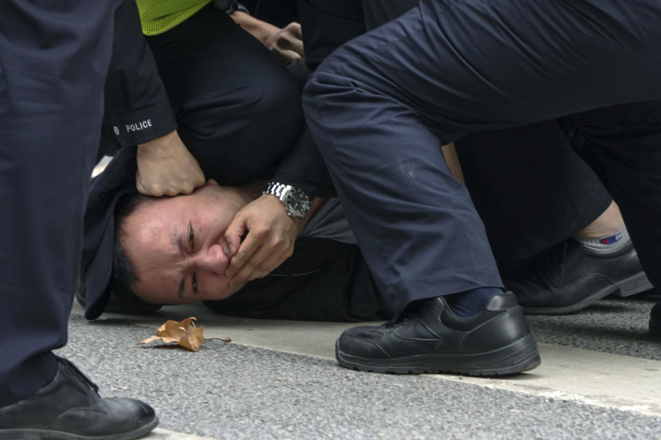 FILE - Chinese policemen pin down a protester and covered his mouth during a protest on a street in Shanghai, China on Nov. 27, 2022. Thousands of people demonstrated across China in what came to be called the White Paper movement, after the blank sheets of paper protesters used to represent the country's strict censorship controls. One year later, China has all but forgotten the protests. The state reacted quickly, breaking up the marches with arrests and threats and ending COVID-19 controls. (AP Photo, File)