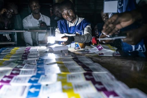 Independent National Electoral Commission (CENI) officials at a school in Lubumbashi count votes during a power cut, watched by observers