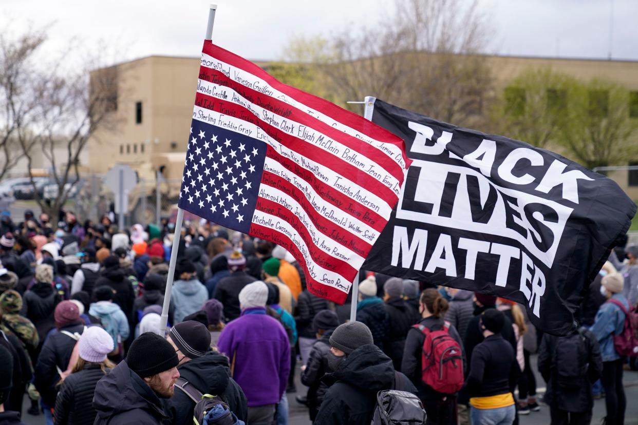 A demonstrator carries a flag bearing the names of Black and Latino homicide victims at a Tuesday rally outside the Brooklyn Center Police Department.