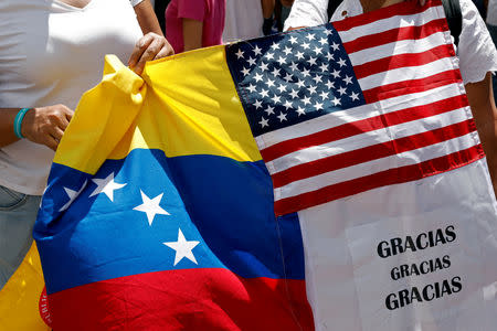 FILE PHOTO: Supporters of the Venezuelan opposition leader Juan Guaido, who many nations have recognized as the country's rightful interim ruler, hold a banner with Venezuelan and U.S. flags during a rally to demand President Nicolas Maduro allow humanitarian aid to enter the country, in Caracas, Venezuela February 23, 2019. The message reads "Thank you". REUTERS/Carlos Jasso/File Photo