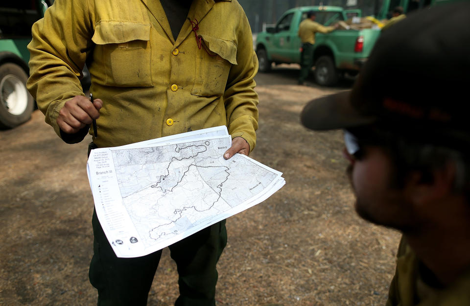 GROVELAND, CA - AUGUST 25:  U.S. Forest Service firefighters look at an incident map as they take a break from battling the Rim Fire at Camp Mather on August 25, 2013 near Groveland, California. The Rim Fire continues to burn out of control and threatens 4,500 homes outside of Yosemite National Park. Over 2,000 firefighters are battling the blaze that has entered a section of Yosemite National Park and is currently 7 percent contained.  (Photo by Justin Sullivan/Getty Images)