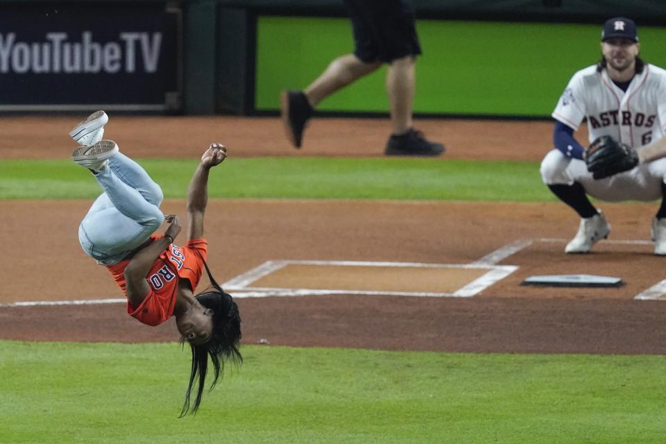 Gymnast Simone Biles does a flip before throwing the ceremonial first pitch before Game 2 of the baseball World Series between the Houston Astros and the Washington Nationals Wednesday, Oct. 23, 2019, in Houston. (AP Photo/Eric Gay)