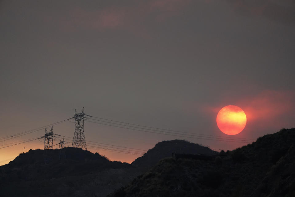 The sun sets through smoke created by the Ranch Fire, Thursday, Aug. 13, 2020, in Azusa, Calif. Heat wave conditions were making difficult work for fire crews battling brush fires and wildfires across Southern California. (AP Photo/Marcio Jose Sanchez)