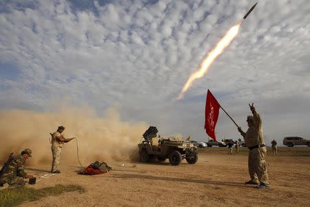 Shi'ite fighters launch a rocket during clashes with Islamic State militants on the outskirts of al-Alam, Iraq in this March 8, 2015 file photo. REUTERS/Thaier Al-Sudani/Files