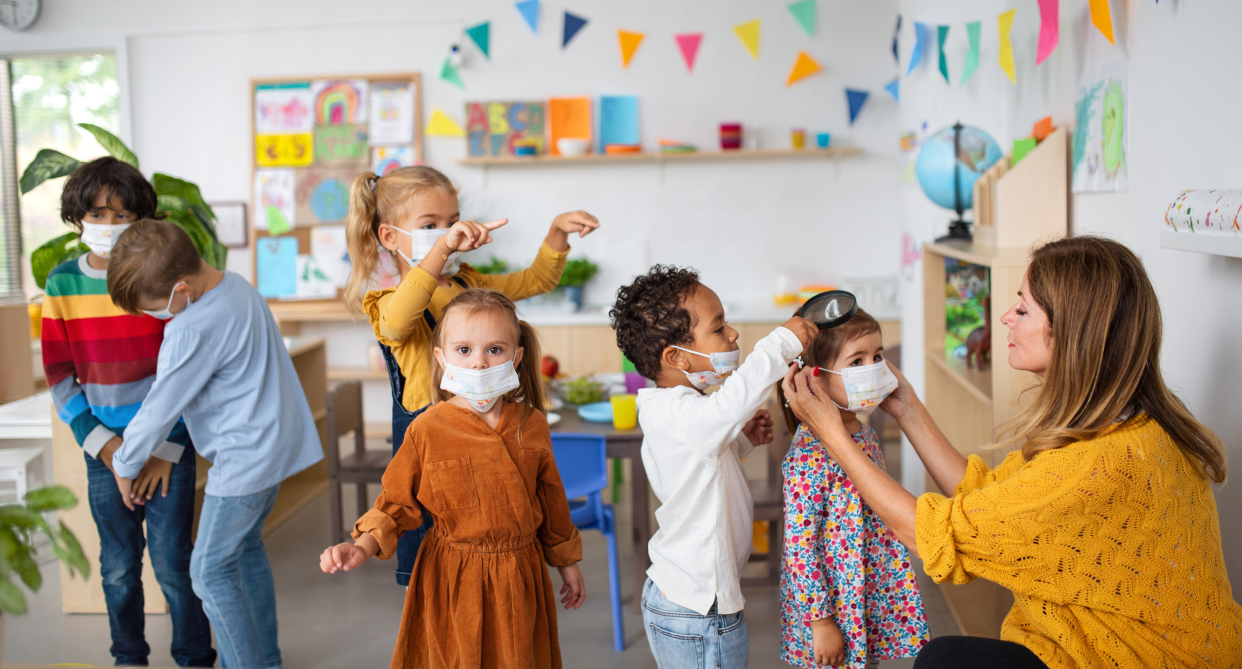 face masks, group of children in classroom wearing face masks with teacher helping them put on face masks