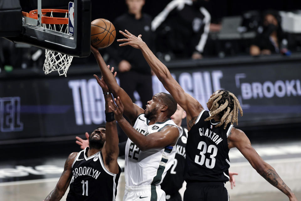 Milwaukee Bucks forward Khris Middleton (22) drives to the basket between Brooklyn Nets guard Kyrie Irving (11) and forward Nicolas Claxton (33) during the first half of Game 1 of an NBA basketball second-round playoff series Saturday, June 5, 2021, in New York. (AP Photo/Adam Hunger)