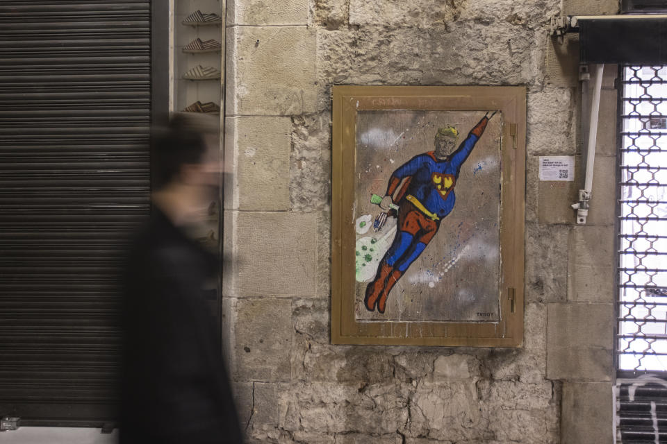 BARCELONA, SPAIN - OCTOBER 07: A person walks by the latest work by  italian urban artist Tvboy 'What doesn't kill you makes you stronger. Or not?' featuring Donald Trump on October 07, 2020 in Barcelona, Spain. A “SuperTrump” character appeared last night in Barcelona, in Plaça Sant Jaume / Carrer del Bisbe. The U.S. President is painted in Superman’s costume surrounded by clouds of COVID-19 viruses and flying through the sky.  (Photo by Xavi Torrent/Getty Images)