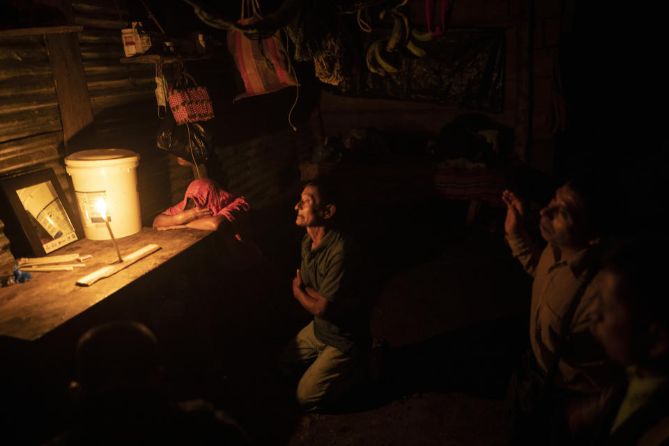 Hector Cal, center, and his wife Paulina Jonay, pray accompanied by an evangelical minister, days after their 26-year-old son Victor began his journey to the United States, in their home in the makeshift settlement Nuevo Queja, Guatemala, Sunday, July 11, 2021. Victor Cal contacted a distant cousin in Miami who agreed to advance the $13,000 to buy a coyote package that offers two attempts to enter the U.S. (AP Photo/Rodrigo Abd)