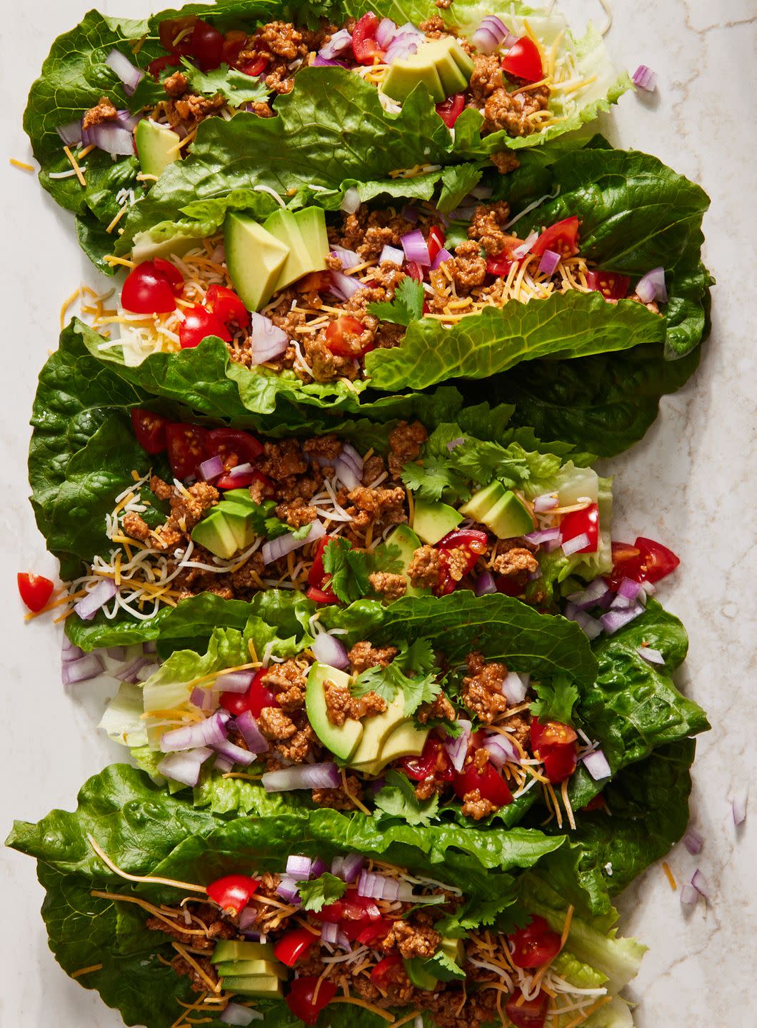 turkey taco lettuce wraps topped with avocado, tomato, red onion, and cilantro