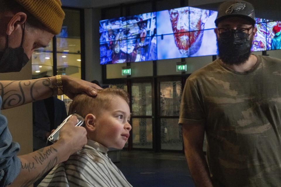 Three-year-old Ole van Santen gets a haircut at the Van Gogh museum in Amsterdam, Wednesday, Jan. 19, 2022, as Dutch museums, theaters and concert halls played host Wednesday to businesses that are allowed to open to customers as a protest against their own continuing lockdown closures. (AP Photo/Peter Dejong)