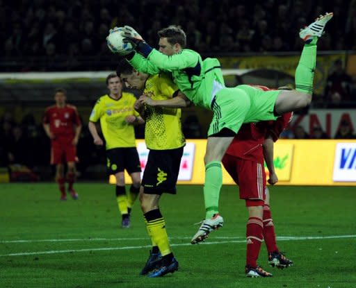 Bayern Munich's goalkeeper Manuel Neuer and Dortmund's Robert Lewandowski fight for the ball during their German first division Bundesliga match in the western German city of Dortmund, on April 11. Dortmund won the match 1-0, going clear at the top with four games left as they look to register their 25th game without defeat