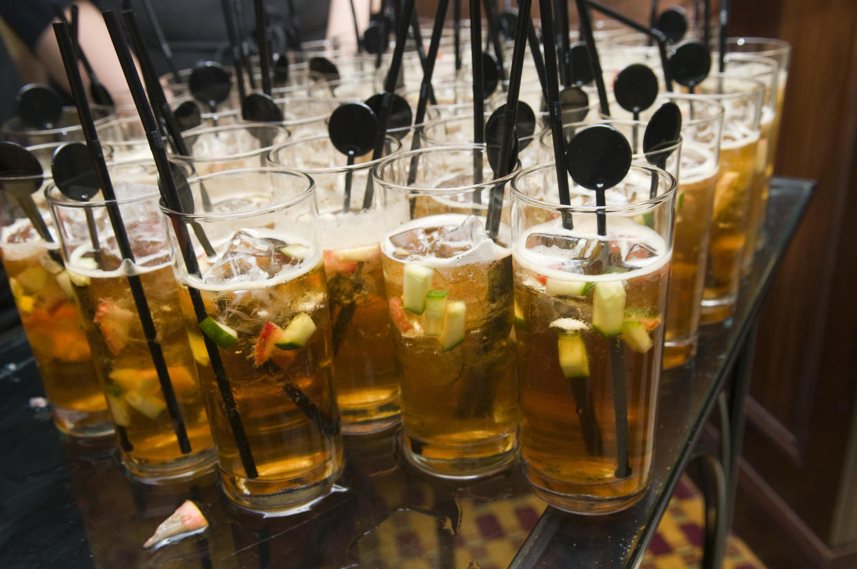 glasses full of pimms with fruit and straws stir sticks.  Narrow focus