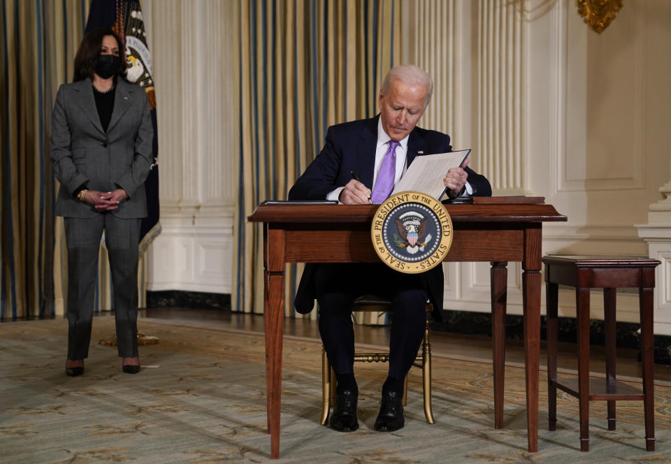 President Joe Biden signs executive orders in the State Dining Room of the White House, Tuesday, Jan. 26, 2021, in Washington. Vice President Kamala Harris listens at left. (AP Photo/Evan Vucci)