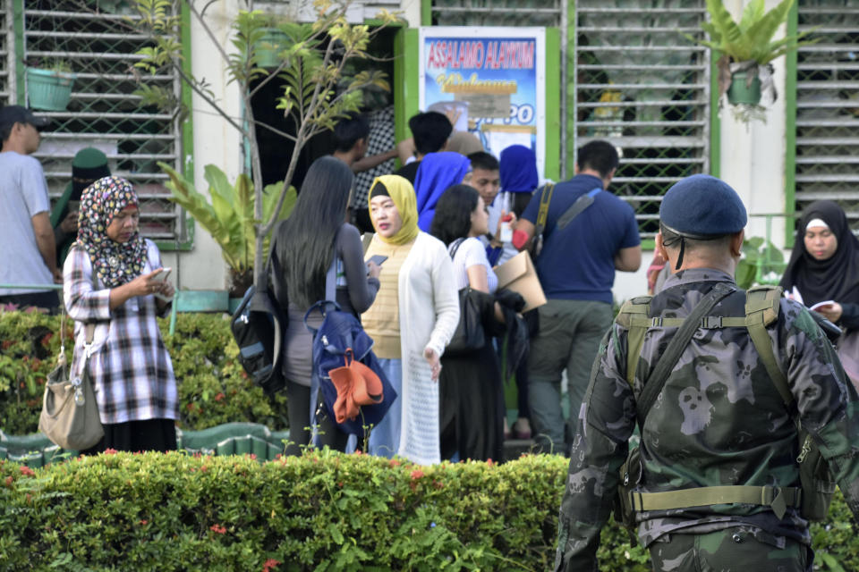 A Philippine police officer, right in foreground, patrols in the compound of an elementary school-turned -polling station in a referendum in Maguindanao province, southern Philippines, Monday, Jan. 21, 2019. Muslims in the southern Philippines voted Monday in a referendum on a new autonomous region that seeks to end nearly half a century of unrest, in what their leaders are touting as the best alternative to a new wave of Islamic State group-inspired militants. (Kyodo News via AP)