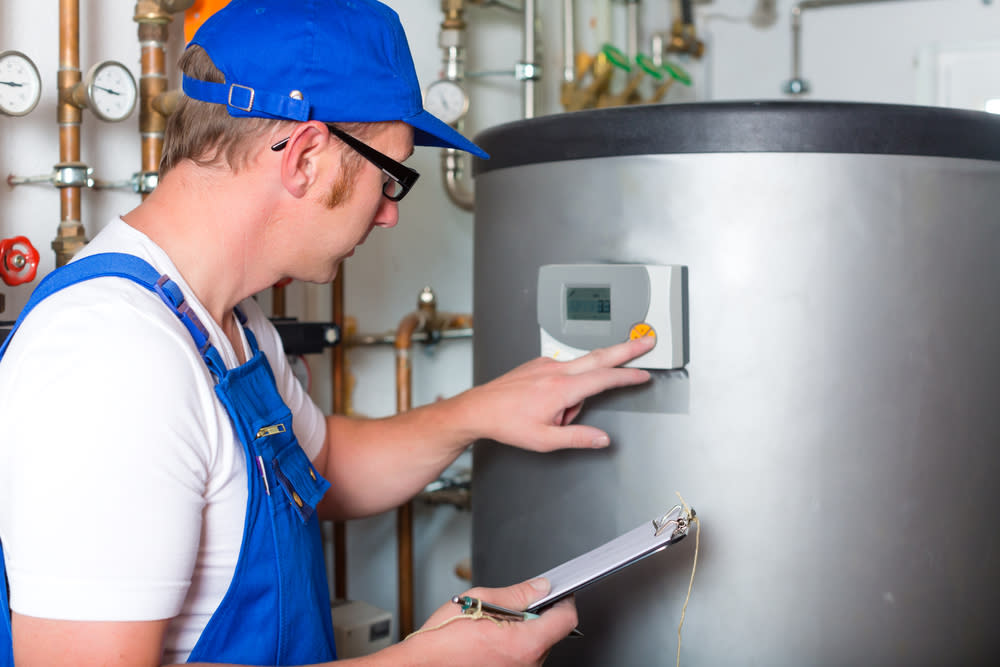 A person presses buttons on a hot water tank.