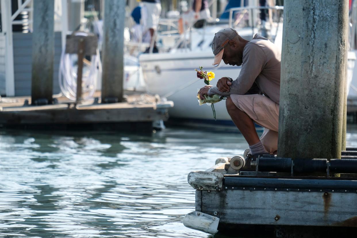 James Miranda, right, of Santa Barbara, holds flowers and takes a moment to reflect at a dock near the Sea Landing at Santa Barbara Harbor on Sept. 2, 2019. A fire raged through a boat carrying recreational scuba divers during a Labor Day weekend retreat.