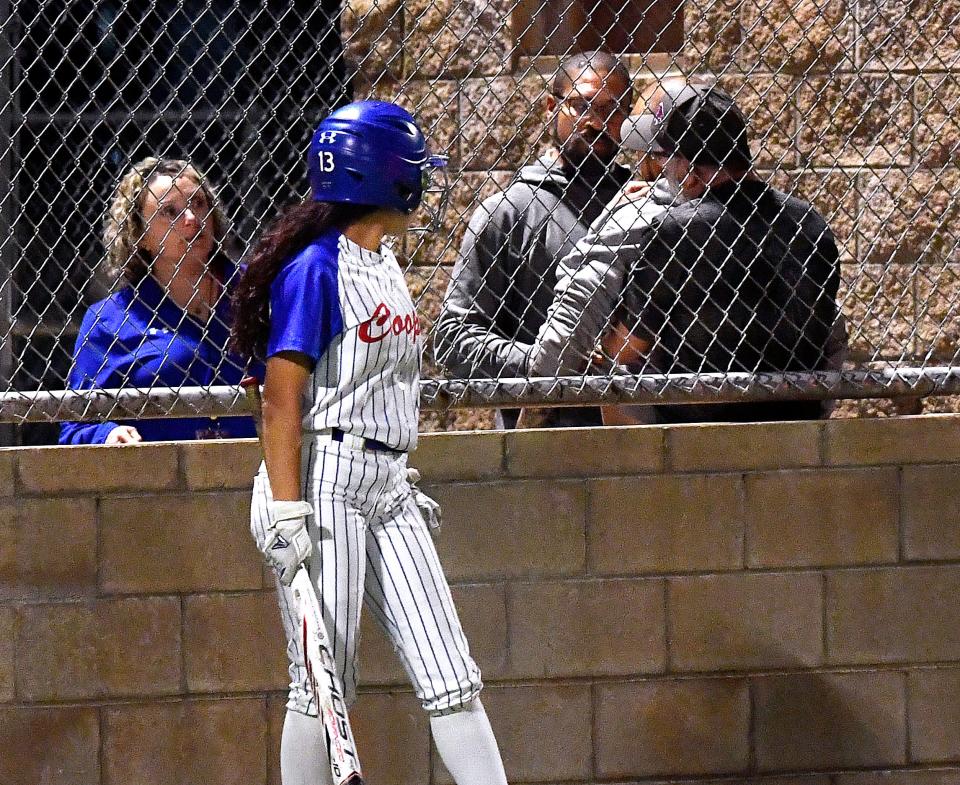 Cooper batter Nadia Garcia watches as two men confront each other while a third restrains one during the ninth inning at Tuesday’s softball game against Lubbock Monterey. Moments earlier, a fight had been observed in the stands and the man being restrained was seen being led away by another. As the game ended, Abilene police officers were seen speaking with attendees at the ball game. No arrests were made.
