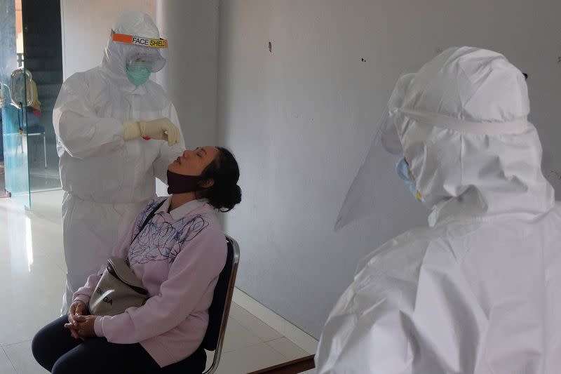 Healthcare worker takes a swab sample from a woman at a traditional market amid coronavirus disease (COVID-19) outbreak in Denpasar