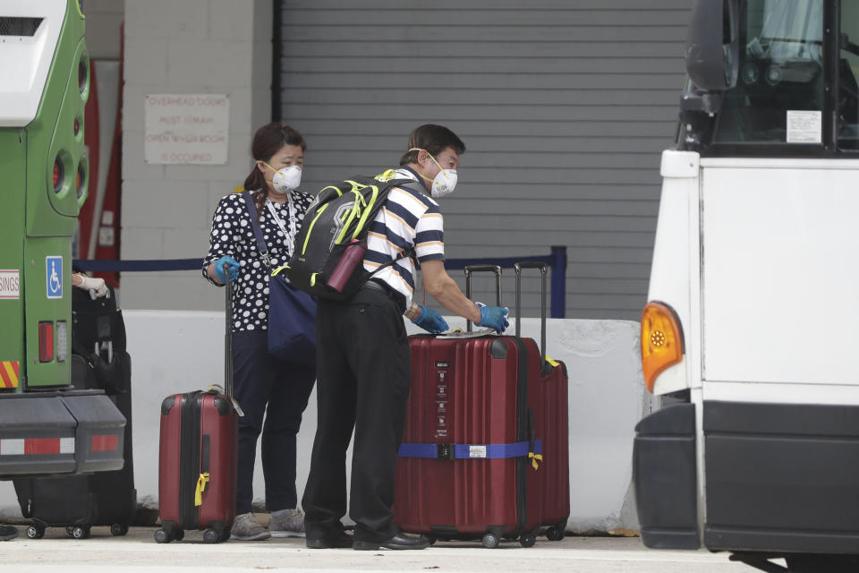 Passengers from the Coral Princess cruise ship prepare to board busses on the way to the airport at PortMiami during the new coronavirus outbreak, Monday, April 6, 2020, in Miami. According to Princess Cruises, disembarkation of guests is expected to take several days due to limited flight availability. (AP Photo/Wilfredo Lee)