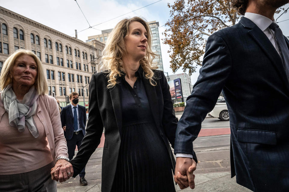 Elizabeth Holmes, founder and former CEO of blood testing and life sciences company Theranos, walks with her mother Noel Holmes and partner Billy Evans into the federal courthouse for her sentencing hearing on November 18, 2022 in San Jose, Calif. (Amy Osborne / AFP via Getty Images file)