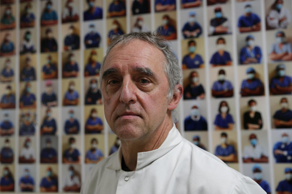 Dr. Philippe Montravers poses in front of a collection of portraits of medical staff at Bichat Hospital, AP-HP, in Paris, Wednesday, Dec. 2, 2020. Even for hospital staff for whom death is a constant, witnessing the loss of a fellow human being to COVID-19 is a churn of emotions. At the Paris hospital that recorded the first virus death outside Asia, nurses and paramedics in the intensive care unit have their own coping mechanisms. (AP Photo/Francois Mori)