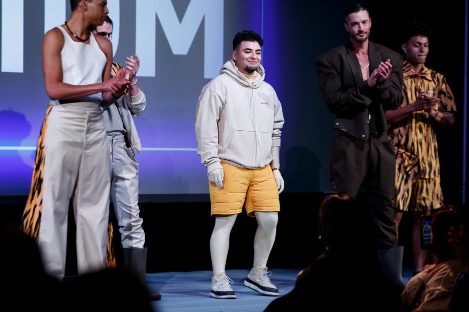 Dustin Argumedo, center, a recent graduate of the Fashion Institute of Design and Merchandising waves to the audience after models debuted his collection during Fashion Week El Paseo on Thursday, March 24, 2022. 