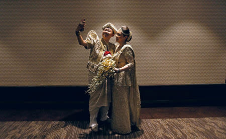 A Chinese wedding couple take selfies before start of the mass wedding ceremony for fifty Chinese couples in Colombo, Sri Lanka December 17, 2017. REUTERS/Dinuka Liyanawatte