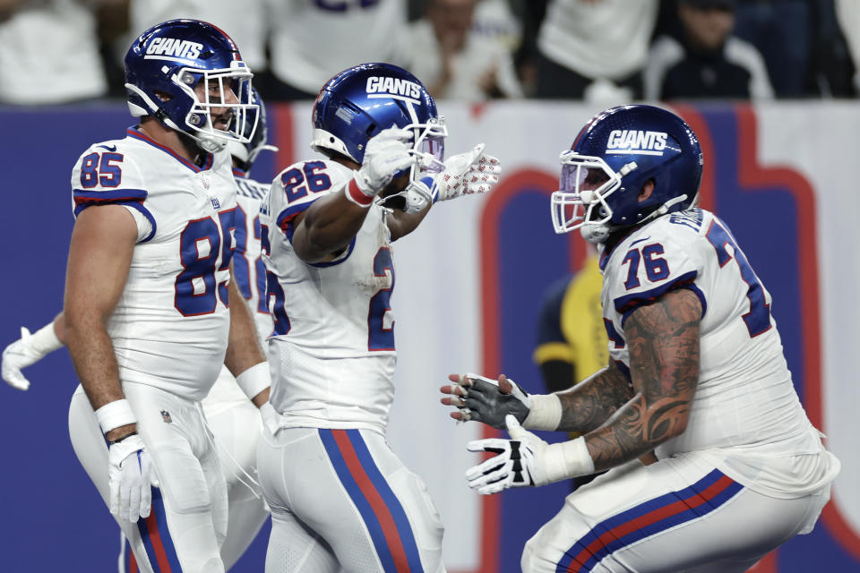 New York Giants running back Saquon Barkley (26) celebrates with guard Jon Feliciano (76) and fullback Chris Myarick (85) after scoring a touchdown against the Dallas Cowboys during the third quarter of an NFL football game, Monday, Sept. 26, 2022, in East Rutherford, N.J. (AP Photo/Adam Hunger)