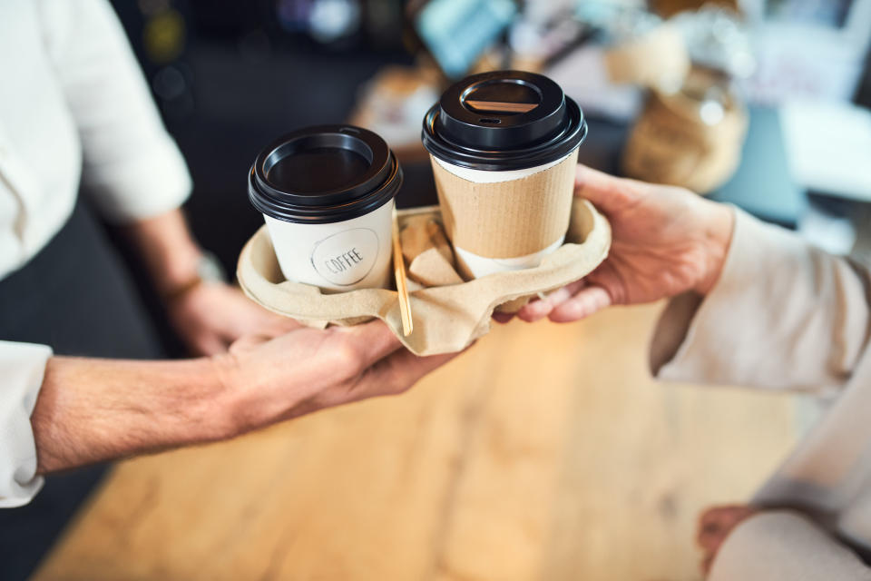 barista handing a tray of drinks to a customer