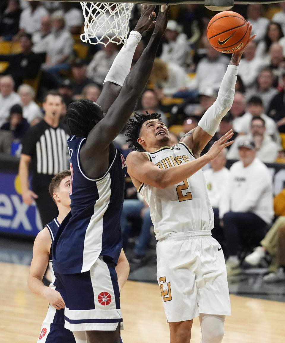 Colorado guard KJ Simpson, right, drives to the basket as Arizona center Oumar Ballo defends in the second half of an NCAA college basketball game Saturday, Feb. 10, 2024, in Boulder, Colo. (AP Photo/David Zalubowski)