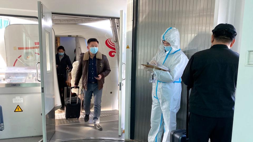 Passagiere tragen Schutzmasken und verlassen ein Flugzeug nach der Ankunft am Wuhan Tianhe International Airport.