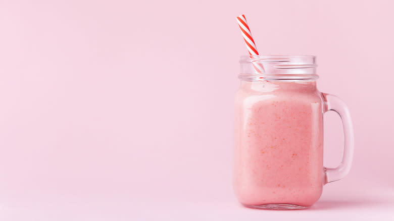 Pink smoothie in glass cup with straw