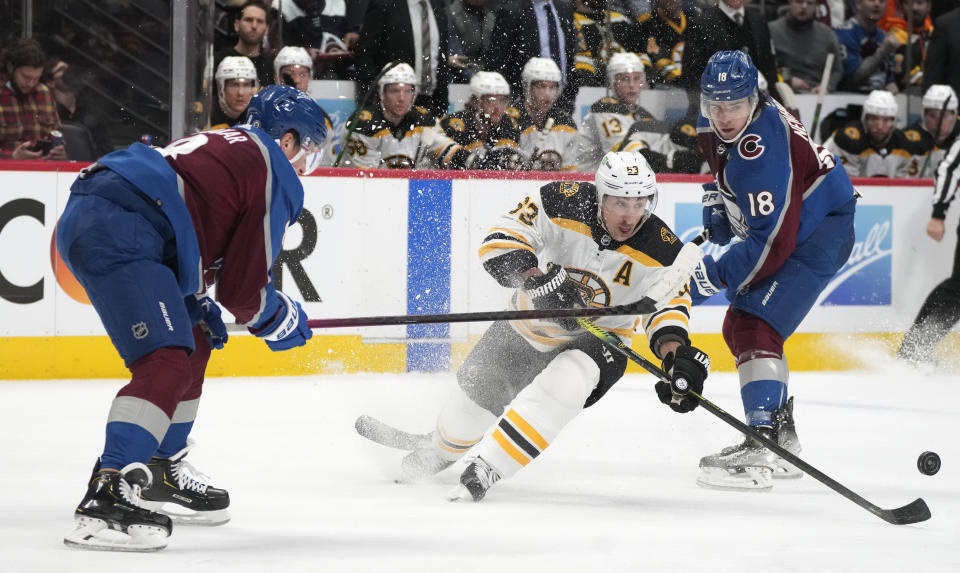 Boston Bruins left wing Brad Marchand, center, fights to control the puck while driuving between Colorado Avalanche defenseman Cale Makar, left, and center Alex Newhook in the second period of an NHL hockey game Wednesday, Jan. 26, 2022, in Denver. (AP Photo/David Zalubowski)