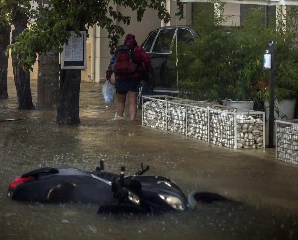 A man walks into a flooded road during a storm at the port of Argostoli, on the Ionian island of Kefalonia, western Greece, Friday, Sept. 18, 2020. A powerful tropical-like storm named Ianos battered the western islands of Zakynthos, Kefalonia, and Ithaki overnight, causing flash flooding, property damage, power outages, and road closures mostly from downed trees, police and local authorities said. (AP Photo/Nikiforos Stamenis)