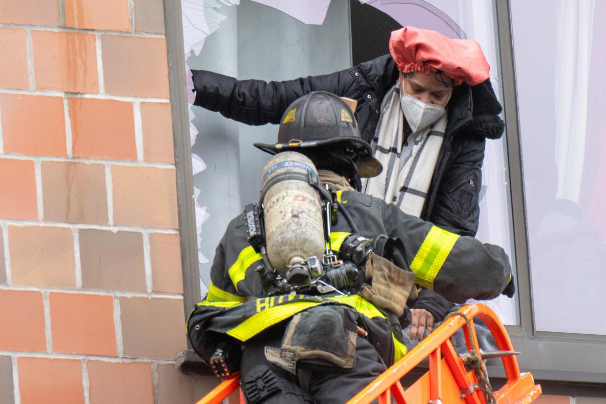 Firefighters hoist a tower ladder to rescue people through their windows in the Bronx on Sunday, Jan. 9, 2022.