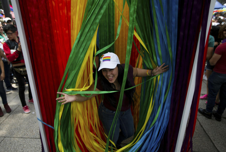 A reveler poses for a photo behind a closet with a curtain made with the colors of the rainbow during the gay pride parade in Mexico City, Mexico, Saturday, June 29, 2019. (AP Photo/Fernando Llano)