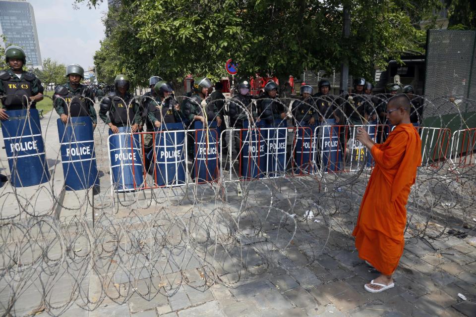 A Buddhist monk takes a photo of riot police standing at Freedom Park in Phnom Penh, Cambodia, Thursday, May 1, 2014. Security forces have beaten demonstrators after a May day rally held in defiance of a government ban on public protests in the Cambodian capital. Nearly 1,000 factory workers and supporters of the opposition Cambodia National Rescue Party had gathered on the streets outside the city's Freedom Park, which had been barred to demonstrators and sealed off. (AP Photo)