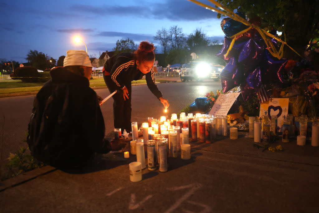 Mourners light candles at a makeshift memorial.