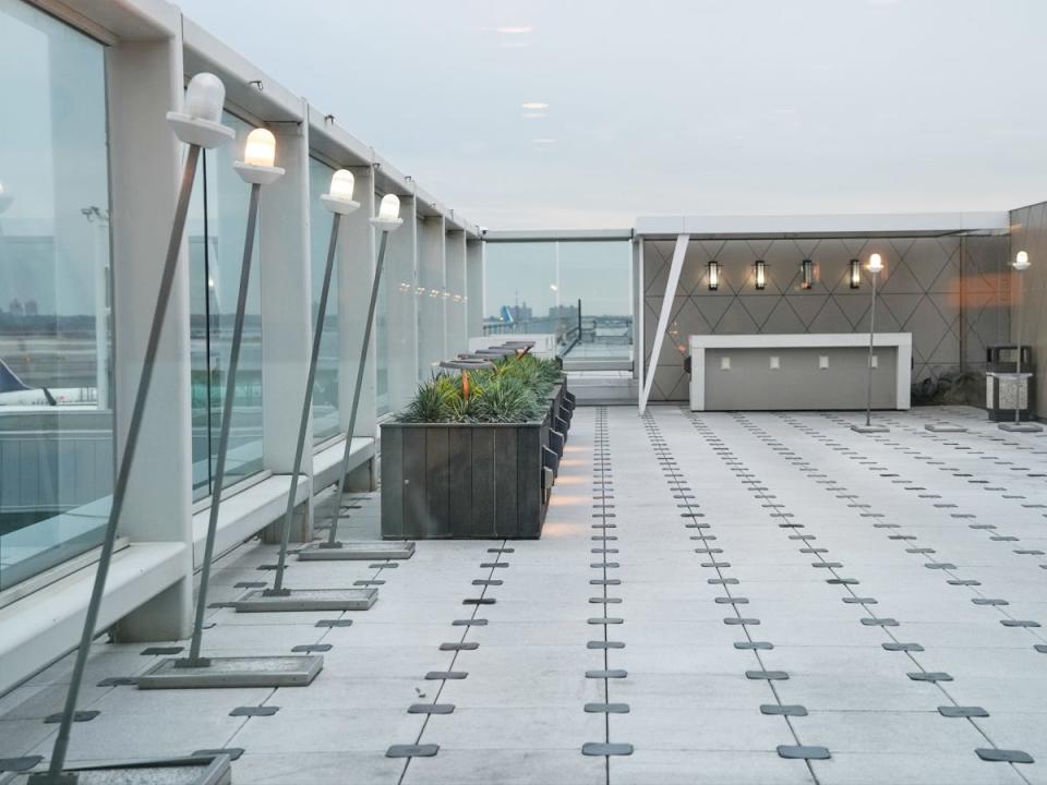 Terrace with some green plants and modern light fixtures. The floor is white and black