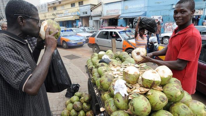 A man drinks a coconut water by the roadside on the eve of presidential elections, in Accra on December 6, 2008